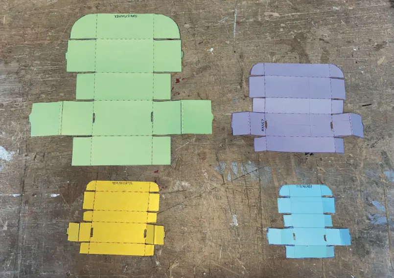 Quatre desplegables de capsa en cartolina de colors, un per a cada mida de joguina